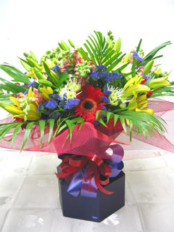 Red Gerbera Special - Yellow asiatic lillies, red gerberas, orange anthirrhinum, white spiky chrysanthemums, blue statice and palm leaves, in a vox wrapped with red tulle.  What a cheerful mix.<br><br>Code:554-5773-554-0000062482