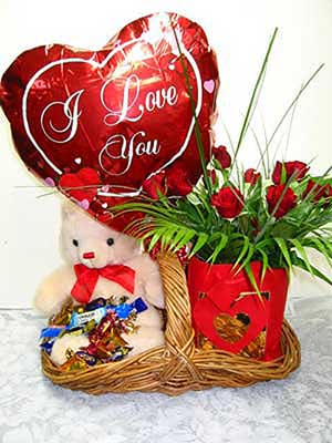 Romance 'n Blossom - A beautiful woven willow basket contains all that he/she could want from you. A dozen red roses with palm leaves and bear grass, a bear and a balloon. A box of Cadbury's chocolates completes the picture<br><br>Code:554-5963-554-0000062457