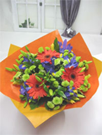 Tangy Orange - Vibrant orange gerberas with a cool touch of green chrysanthemum, yellow lillies and blue iris. Wrapped in colours to complement and finished with a bow. Bright and cheery, guaranteed to make someone smile.<br><br>Code:554-1180-554-0000062433
