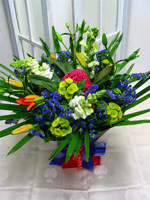 Supreme Funk - A stunning mix of orange asiatic lillies, green chrysanthemums, purple statice, white antirrhinums. A waratah surprises the eye in the centre of the arrangement and a line of fan palm finishes the arrangement.<br><br>Code:554-9587-554-0000062398