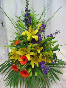 Tropical Lillies - Gorgeous yellow asiatic lillies make a statement with purple stock orange gerberas and lush tropical palm leaves and beargrass.<br><br>Code:554-5216-554-0000062366